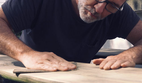 Close-up of male carpenter sanding wood in workshop