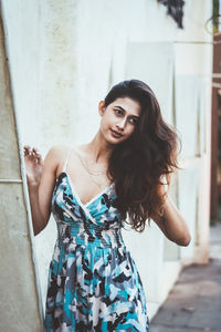 Portrait of smiling young woman standing against wall