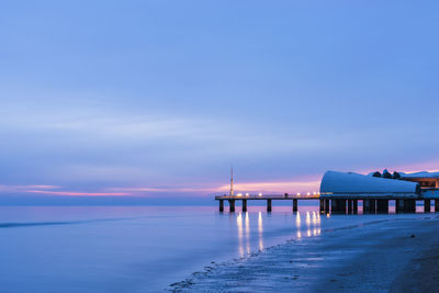 Pier over sea against blue sky at sunset