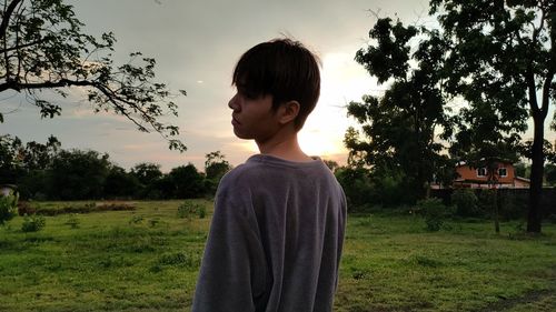 Full length of boy standing on field against sky