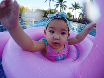 Close-up portrait of toddler with inflatable ring floating on swimming pool