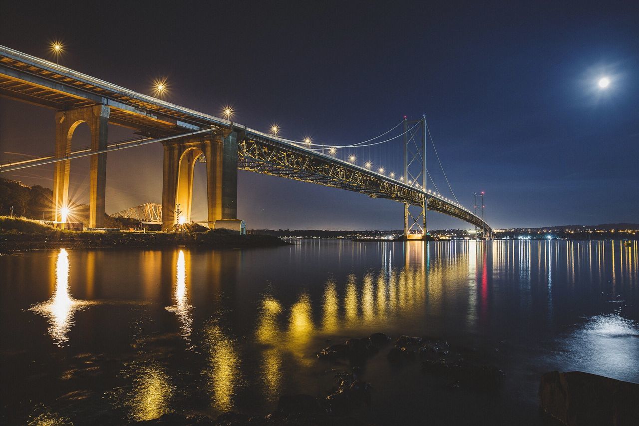 SUSPENSION BRIDGE OVER RIVER AT NIGHT