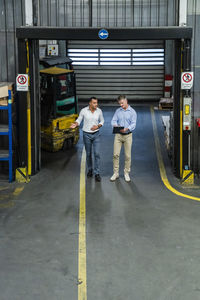 Male professionals discussing business strategy while walking in factory
