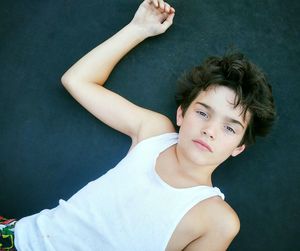 High angle portrait of boy lying on floor outdoors