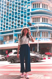 Portrait of young woman standing against building in city