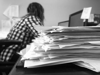 Stack of papers on table with woman in background