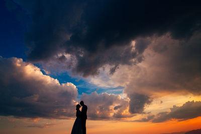 Low angle view of silhouette person standing against sky during sunset