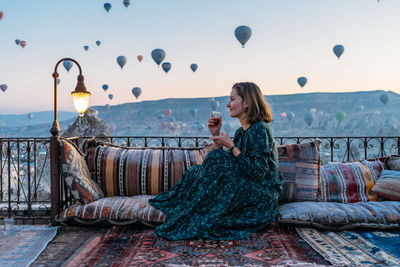 Woman drinking early morning tea with hot air balloons in cappadocia