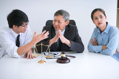 Lawyers discussing while sitting at desk in courthouse