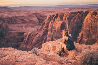 Rear view of woman sitting on rock formation