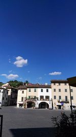 Buildings by street against blue sky