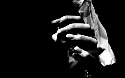 Close-up of hands holding cigarette against black background