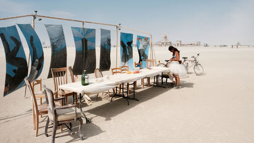 Man on chair by sea against sky