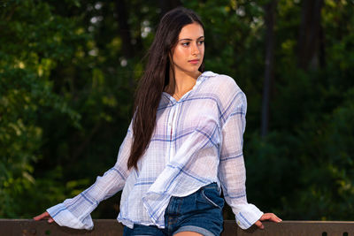 Portrait of beautiful young woman against trees