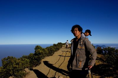Man standing by sea against clear blue sky