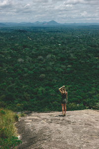 Rear view of woman standing on mountain against sky