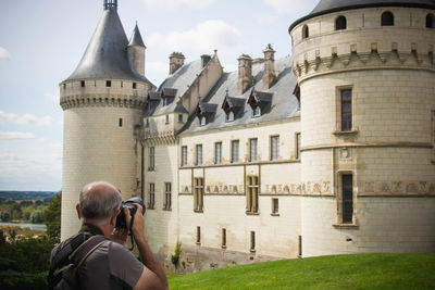 Man photographing building with mobile phone against buildings