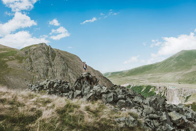 Man standing on rock against blue sky