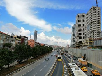 Vehicles on road amidst buildings in city against sky