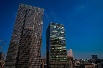 Low angle view of skyscrapers against blue sky
