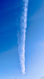 Low angle view of vapor trails against blue sky