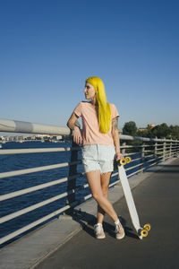 Woman standing by railing against clear sky