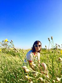 Portrait of woman wearing sunglasses on field against clear sky