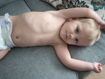 Portrait of shirtless baby lying on bed