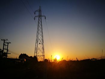 Silhouette of electricity pylon against dramatic sky