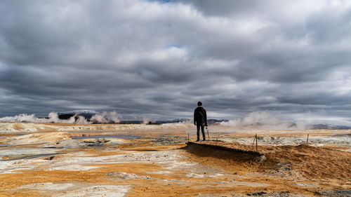 Rear view of man standing on land against sky in hverir, iceland