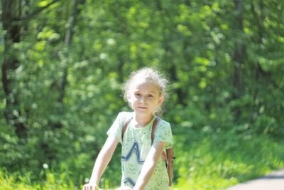 Portrait of girl standing against trees