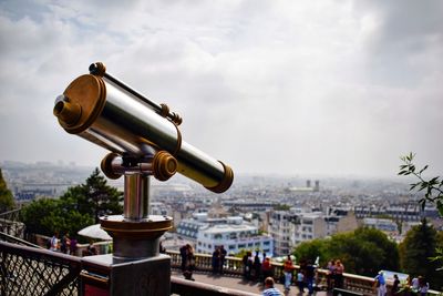 Close-up of coin-operated binoculars against cityscape