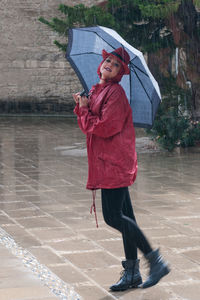 Full length of woman standing with umbrella during rainfall