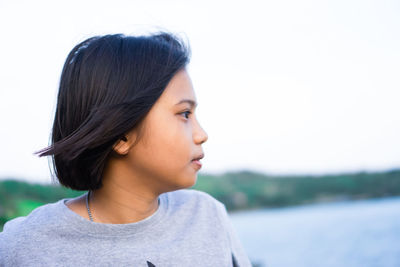 Girl looking away against sky