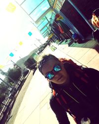 Portrait of smiling young woman standing against built structure