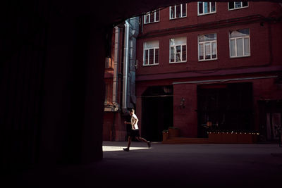 Side view of unrecognizable male runner jumping on street while training in city in summer