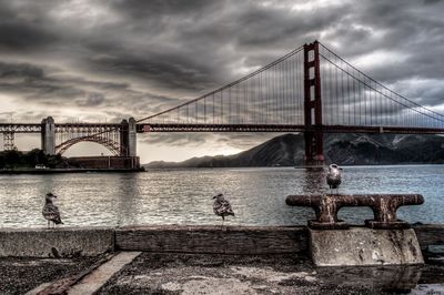 View of suspension bridge against cloudy sky