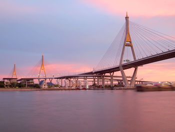 View of suspension bridge over river at sunset