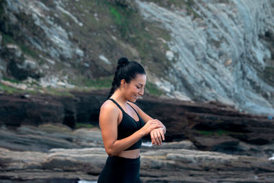 Side view of young woman standing on rock