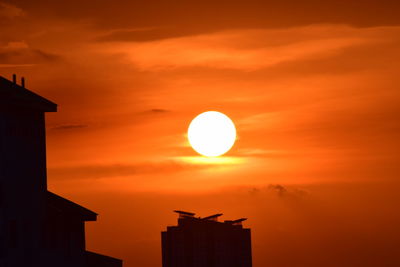 Low angle view of silhouette building against orange sky