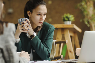 Mid adult man using mobile phone while sitting on table