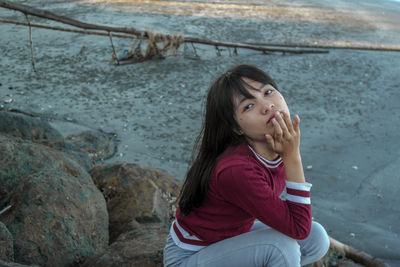 Portrait of girl sitting on rock by river