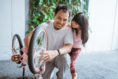 Father repairing bicycle with daughter at home