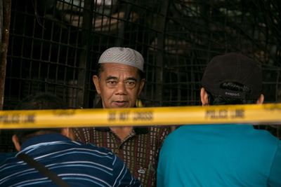 People by cordon tape against metallic fence