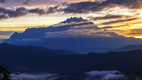 Scenic view of mountains against dramatic sky during sunset