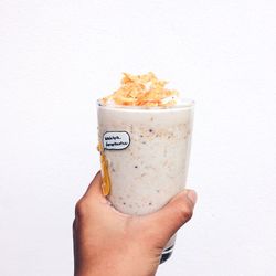 Close-up of hand holding drink against white background