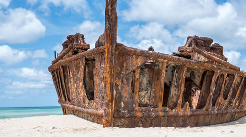 Low angle view of abandoned ship on beach against sky