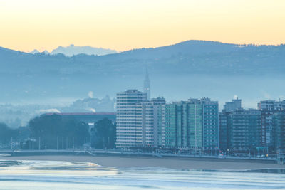 Buildings in city against sky during sunset