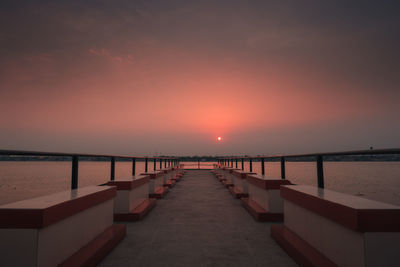 Pier over sea against sky during sunset