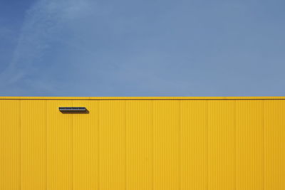 Low angle view of yellow wall against blue sky